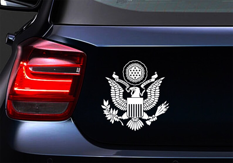 Pode incluir: Adesivo de vinil branco do Grande Selo dos Estados Unidos, com uma &aacute;guia de asas abertas, um escudo com listras verticais e uma faixa com as palavras "E Pluribus Unum".