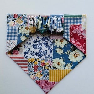 Puede incluir: Un bandana de tela de patchwork con una variedad de patrones florales y geométricos en tonos de azul, rojo, amarillo y blanco.