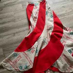 Peut inclure: Une longue jupe rouge et blanche avec un motif tourbillonnant. La jupe est faite d'un tissu léger et a une silhouette fluide.