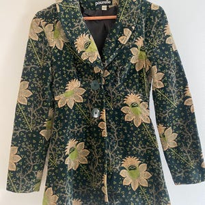 Peut inclure: Une veste en velours vert à imprimé floral. La veste a un col, une fermeture à boutons et des manches longues. La marque "pour elle" est visible sur l'étiquette.