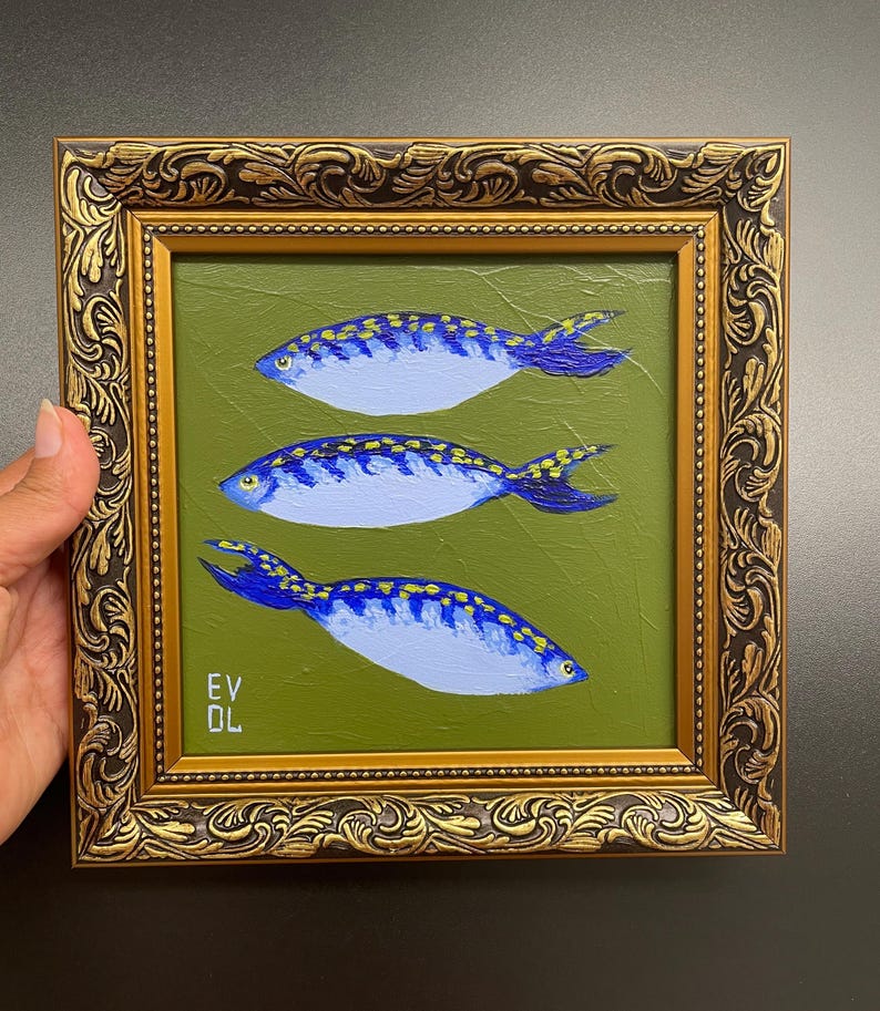 May include: A framed painting featuring three blue and yellow fish on a green background. The fish are painted with detailed scales and fins. The frame is ornate with gold and brown tones. The artist's initials, EV DL, are visible in the lower left corner.