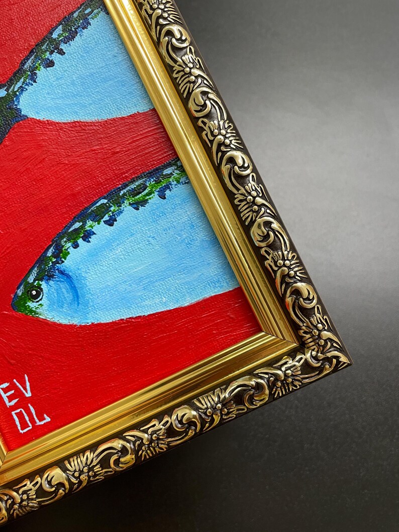 May include: An original oil painting of fish with red and blue hues, framed in a gold ornate frame. The artwork features a close-up view of the fish, with the artist's initials visible in the lower left corner.