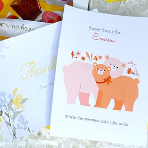 May include: Two greeting cards with text and illustrations. One card says "Thank You" with floral accents. The other says "Sweet Treats for Emma" with a bear illustration and the text "You're the sweetest kid in the world!"
