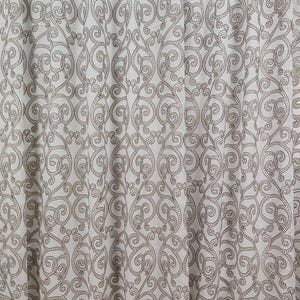 Può includere: Pannello tenda bianco sporco con un motivo ripetuto marrone di volute ornate. Il tessuto è semitrasparente, consentendo alla luce di filtrare. Il design presenta una disposizione simmetrica di linee a spirale e dettagli puntinati.