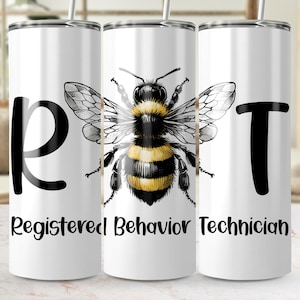 May include: A white tumbler featuring a bee design in black and yellow. The tumbler has the letters "RBT" in black, with the words "Registered Behavior Technician" below the bee illustration. It includes a silver straw.