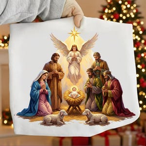 Puede incluir: Una tela blanca con una escena de la Natividad con María, José, el niño Jesús, ángeles y los tres reyes magos. La obra de arte es de estilo clásico con colores cálidos y una estrella arriba.