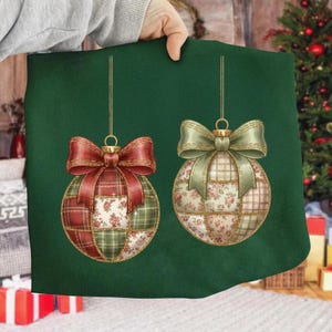 Może przedstawiać: Dwie bombki choinkowe z patchworkowymi wzorami i dużymi kokardami. Jedna bombka ma czerwony wzór w kratę i kwiaty z czerwoną kokardą. Druga ma wzór kwiatowy i w kratę z zieloną kokardą. Obie bombki wiszą na złotych sznurkach.