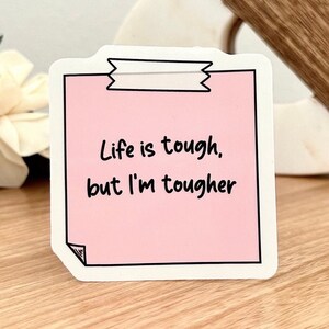Puede incluir: Una nota adhesiva rosa con el texto "Life is tough. but I'm tougher" escrito en negro.