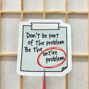May include: White sticker with a blue background and black outline. The sticker has the text "Don't be part of the problem Be the entire problem" with the word "entire" circled in red.