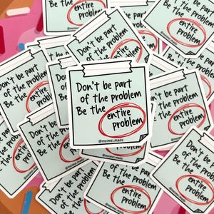 May include: A stack of stickers with a light blue background and black text. The stickers say "Don't be part of the problem. Be the entire problem." with the word "entire" circled in red.