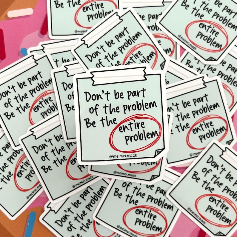 May include: A stack of stickers with a light blue background and black text. The stickers say "Don't be part of the problem. Be the entire problem." with the word "entire" circled in red.