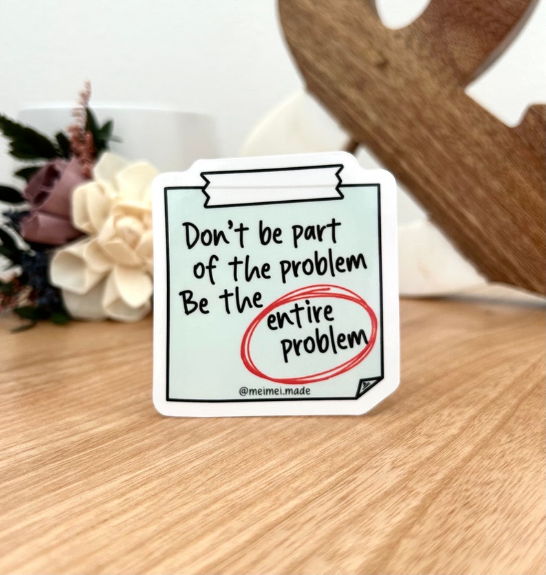 May include: A white sticker with a blue background and black text that reads "Don't be part of the problem. Be the entire problem." The word "entire" is circled in red.