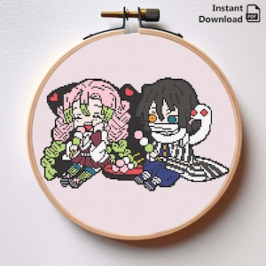 May include: A cross-stitch embroidery hoop featuring two anime-style characters with pink and black hair, set against a light pink background. The text "Instant Download PDF" is visible at the top right.