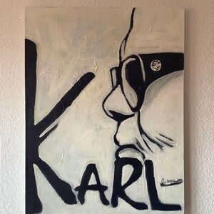 Könnte beinhalten: Schwarzweißes Gemälde einer Person mit Sonnenbrille, auf dem das Wort "KARL" in großen Buchstaben unten geschrieben steht. Das Gemälde ist unten rechts mit "C. 2020" signiert.