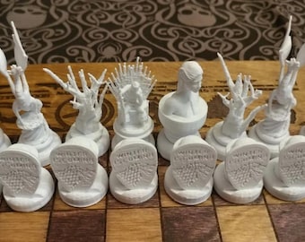 May include: A white chess set with pieces inspired by characters and symbols from the popular fantasy television series Game of Thrones. The pieces are arranged on a wooden chessboard.