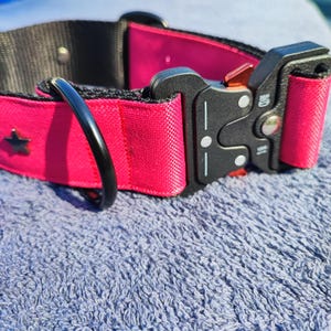 Könnte beinhalten: Ein pinkfarbenes Hundehalsband mit einer schwarzen Schnalle und einem silbernen Stern. Das Halsband hat einen schwarzen D-Ring.