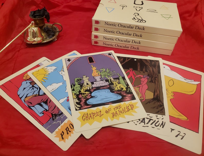 May include: Five tarot cards with colorful illustrations and text. The cards are laid out in a fan shape on a red surface. The card on the top reads "Chapel of the Damned".