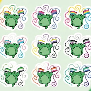 May include: Nine sticker designs featuring a cartoon frog holding different pride flags. The flags include the rainbow, transgender, bisexual, pansexual, genderqueer, asexual, lesbian, non-binary, and intersex flags.