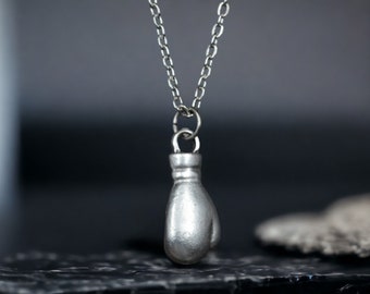May include: A silver chain necklace with a silver boxing glove pendant.