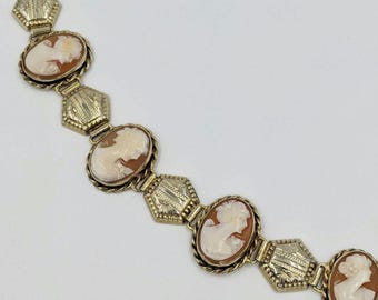 May include: A gold tone bracelet with a chain link design and cameo medallions. Each medallion features a carved profile of a woman.
