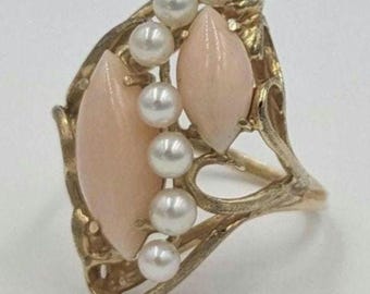 Può includere: Un anello d'oro con un design delicato e intricato che presenta due pietre di corallo rosa e una fila di perle bianche.