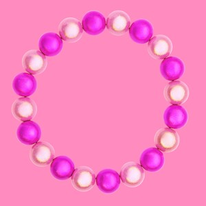 A circular bracelet made of alternating pink and white beads is displayed against a solid pink background.