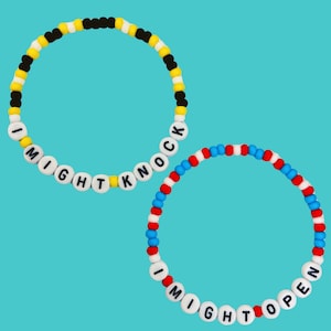 May include: Two beaded bracelets with white letter beads spelling "I MIGHT KNOCK" and "I MIGHT OPEN". One bracelet has yellow, black, and white beads. The other has red, white, and blue beads.