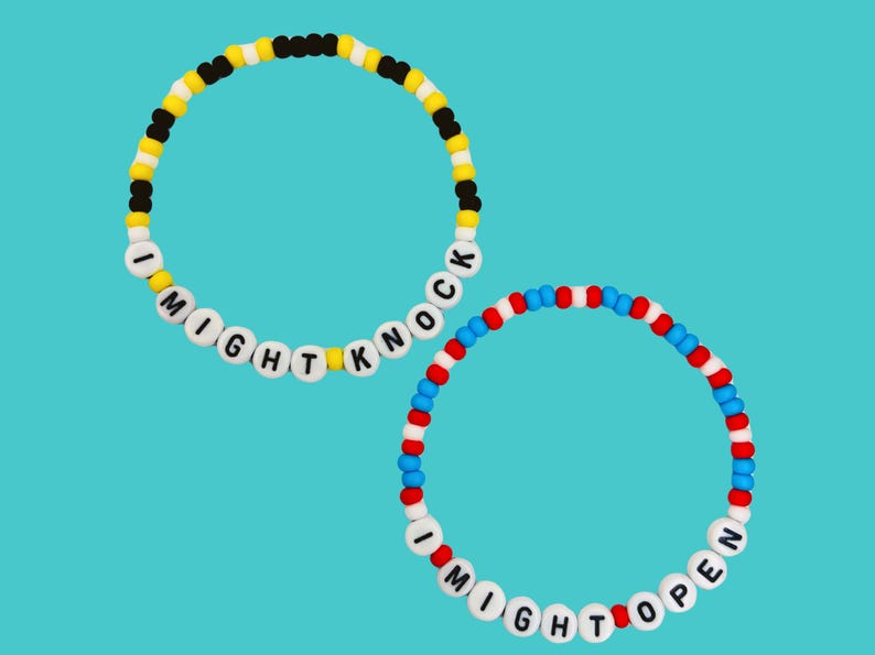 May include: Two beaded bracelets with white letter beads spelling "I MIGHT KNOCK" and "I MIGHT OPEN". One bracelet has yellow, black, and white beads. The other has red, white, and blue beads.