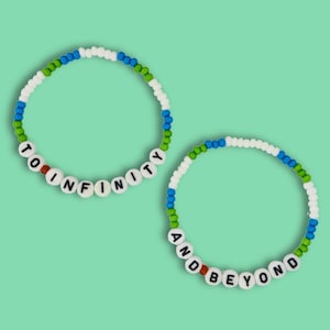 Puede incluir: Dos pulseras de cuentas con cuentas blancas y detalles verdes, azules y naranjas. Las pulseras deletrean "To Infinity" y "And Beyond".