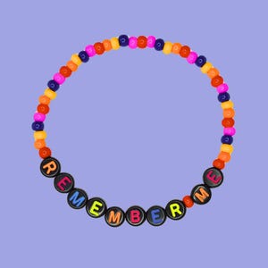 Peut inclure: Un bracelet en perles colorées avec le mot "REMEMBER ME" écrit en perles noires avec des lettres colorées.