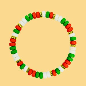 May include: A beaded bracelet featuring red, green, white, and gold-colored beads. The bracelet is made of small, round beads strung together to form a circular shape. The beads are arranged in a repeating pattern of colors.