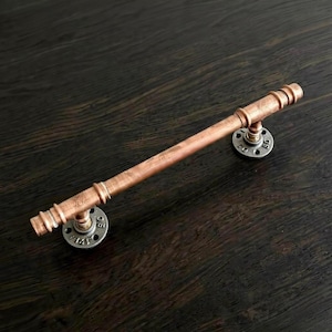 May include: A handmade wooden sign with the text "Welcome" in a handwritten style. The sign is painted white with a distressed finish, and a small green leaf is attached to the top. The sign measures approximately 12 inches wide.