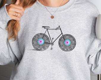 Op de afbeelding: Een grijs sweatshirt met een zwart fietsontwerp. De fiets heeft roze en blauwe bloemen in het midden van elk wiel.