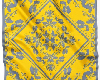 May include: A square scarf featuring a vibrant yellow background with a repeating gray botanical pattern. A large central diamond shape is outlined in gray, containing a symmetrical floral motif. The word OBIMY is printed in small gray letters.