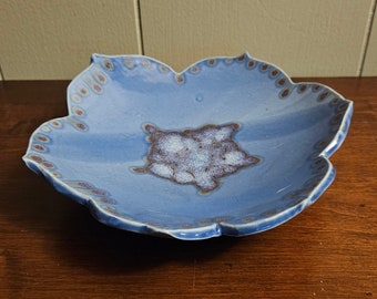 May include: A blue ceramic dish with a scalloped edge and a white and brown design in the center.