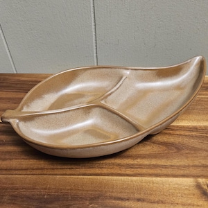 May include: A brown ceramic serving dish shaped like a leaf with three divided sections.