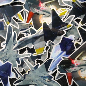 May include: A collection of colorful stickers featuring fighter jets in various poses. The stickers are printed on white paper with black outlines. Some of the stickers have text that says "It's time".