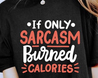 Puede incluir: Camiseta negra con el texto "If only sarcasm burned calories" en letras blancas y coral. La camiseta se combina con unos shorts con estampado de leopardo. Se ve una pulsera y un anillo dorados.
