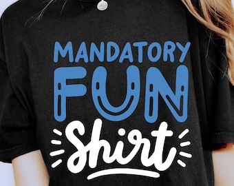May include: Black t-shirt with the words "MANDATORY FUN Shirt" in blue and white. The shirt has a relaxed fit and is worn with leopard print shorts. The overall style is casual and fun.