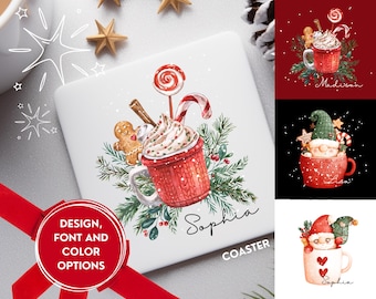 May include: White square coaster featuring a watercolor illustration of a red mug with whipped cream, a gingerbread man, and a candy cane. The word "Sophia" is written in script. The coaster is surrounded by Christmas decorations.