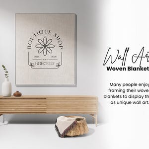 May include: A framed wall art piece with a floral logo and the text "BOUTIQUE SHOP". A wooden console table holds a vase, decorative items, and a woven basket with a blanket. The text "Wall Art Woven Blanket" is also visible.