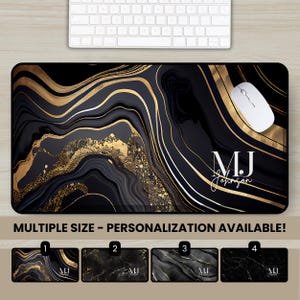 May include: A rectangular desk mat featuring a black and gold marbled pattern with flowing, abstract lines and gold glitter accents. The text MJ Johnson is printed in white on the right side. A white computer mouse rests on the mat surface.