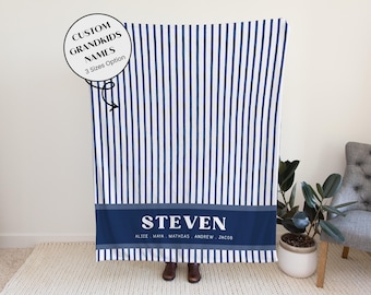 May include: A navy and white striped blanket with a navy blue band at the bottom. The band features the name "STEVEN" in white, with additional names below. Text in a circle reads "CUSTOM GRANDKIDS NAMES 3 Sizes Option".