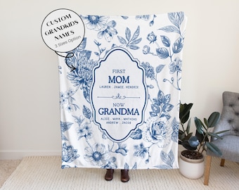 May include: A white blanket with a blue floral pattern and a central framed design. The frame reads "First Mom Now Grandma" with names listed below. Text in a circle reads "Custom Grandkids Names 3 Sizes Option".