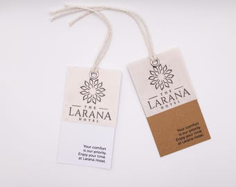 May include: Two rectangular tags with the text "THE LARANA HOTEL" and a floral design. The tags are white and tan with a string attached. The text "Your comfort is our priority. Enjoy your time at Larana Hotel" is printed on the bottom.
