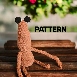 Może przedstawiać: Brązowe szydełkowe stworzenie z czarnymi uszami i długimi ramionami i nogami. Słowo "PATTERN" jest wyświetlane czarnym tekstem. Tekst "ELLIEBEARCROCHET" jest wyświetlany na dole obrazu.