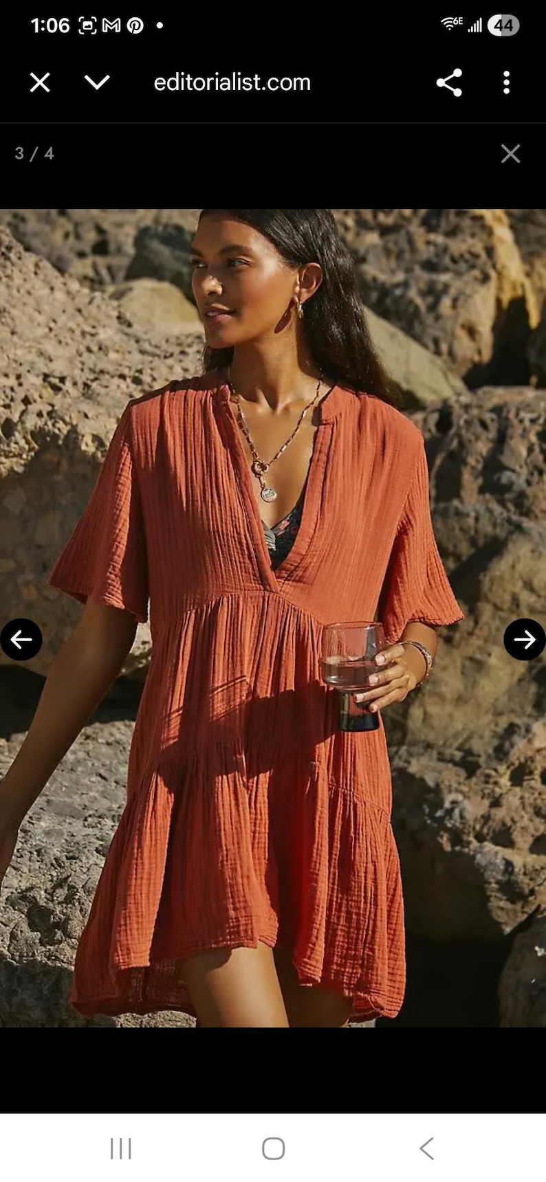May include: Rust-colored short dress with a V-neck and short sleeves. The dress has a tiered, flowing design. The model is holding a glass of water. The website editorialist.com is visible in the image.
