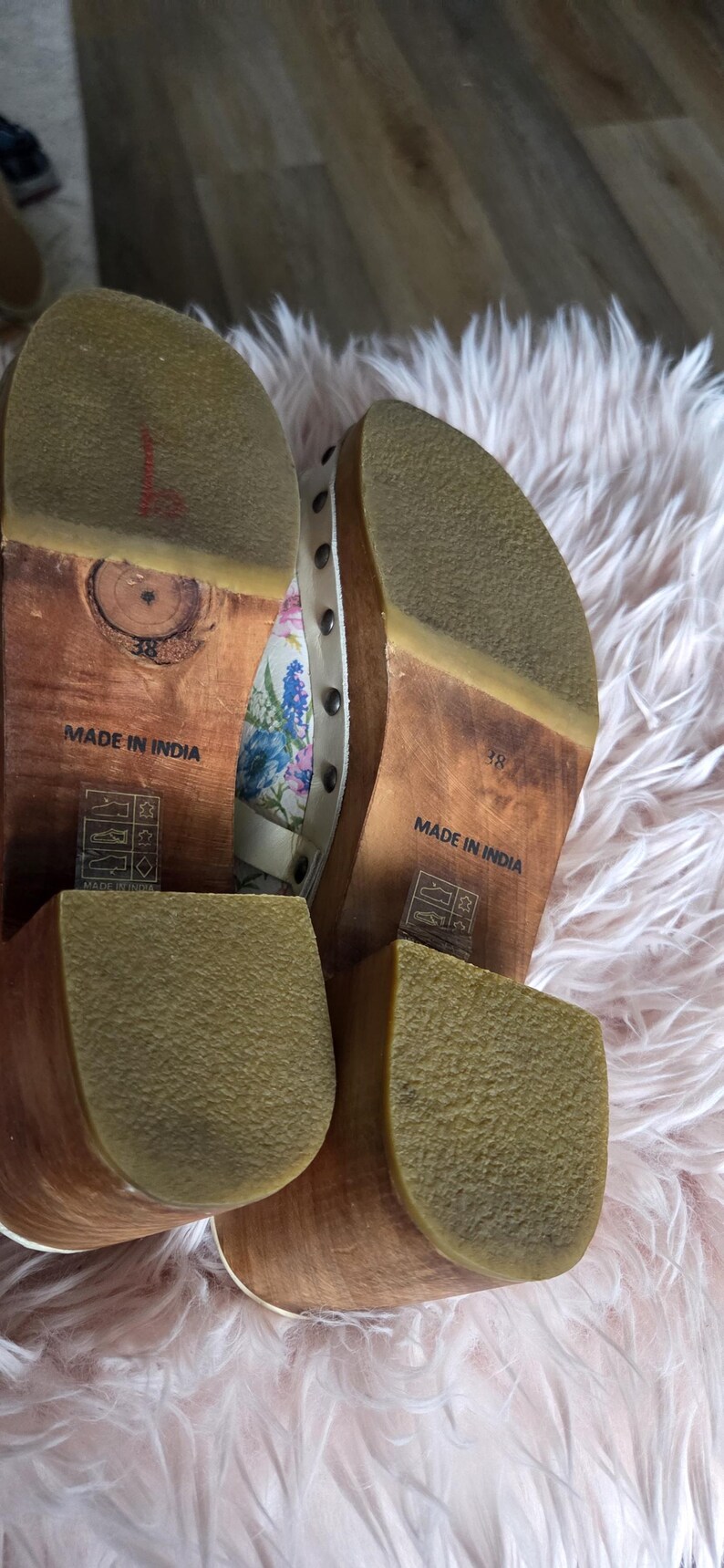May include: Pair of wooden-soled clogs with floral fabric uppers and studded accents. The soles are marked "Made in India" and size 38. The clogs have a light brown wooden base and a rubber sole.
