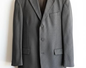 May include: A charcoal gray blazer with a subtle textured pattern. The two-button jacket features notched lapels, a chest pocket, and two flap pockets. The interior lining is a darker brown color.