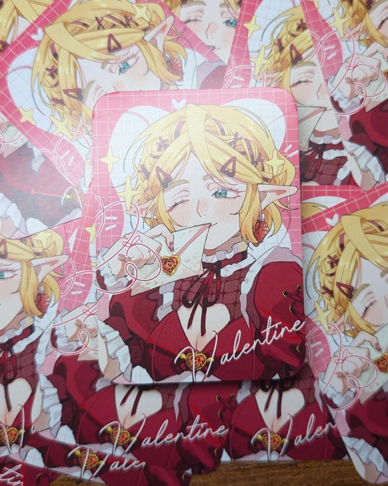 May include: A stack of Valentine's Day themed cards featuring an anime-style illustration of a blonde character with elf ears. The character is wearing a red dress and holding a heart-shaped object. The word "Valentine" is written on the cards.